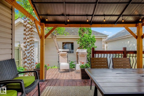 Covered wood-finish deck featuring a durable metal roof, exposed wood beams, and integrated string lighting - 9130 100A Avenue Nw, Edmonton, AB - Outdoor With Deck Patio Veranda With Exterior
