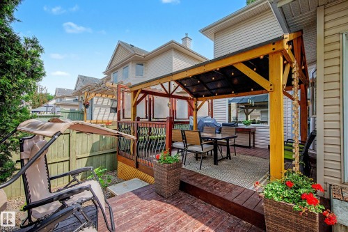 Multi-level wooden deck featuring a covered outdoor dining area with string lighting, a built-in outdoor kitchen unit, and a pergola structure - 9130 100A Avenue Nw, Edmonton, AB - Outdoor With Deck Patio Veranda With Exterior