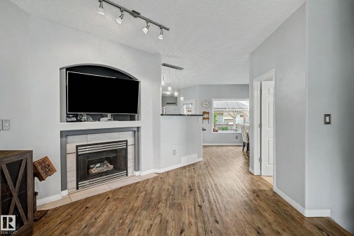Living area featuring wood-finish flooring, a fireplace with tile surround, and an integrated media niche - 9130 100A Avenue Nw, Edmonton, AB - Indoor With Fireplace