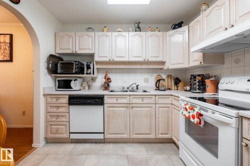 Kitchen featuring light wood-finish cabinetry and a white tiled backsplash - #310 17151 94A Av Nw, Edmonton, AB - Indoor Photo Showing Kitchen With Double Sink