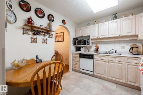 Kitchen featuring light wood-finish cabinetry, white tile backsplash, and a double basin sink - #310 17151 94A Av Nw, Edmonton, AB - Indoor Photo Showing Other Room
