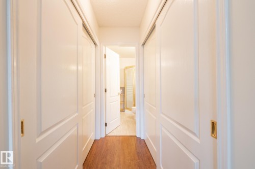 Hallway featuring wood-finish flooring, white panel doors, and recessed lighting - #310 17151 94A Av Nw, Edmonton, AB - Indoor Photo Showing Other Room