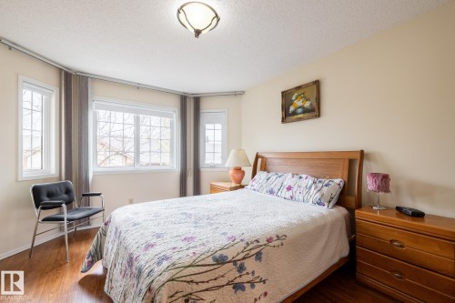 Bright room featuring multiple windows with grid patterns, wood-finish flooring, and a ceiling-mounted light fixture - #310 17151 94A Av Nw, Edmonton, AB - Indoor Photo Showing Bedroom
