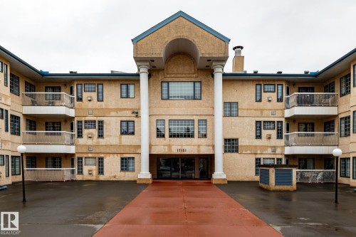 Multi-story building featuring a central entrance with a portico supported by white columns - #310 17151 94A Av Nw, Edmonton, AB - Outdoor With Balcony With Facade