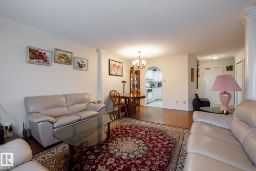 Open-concept living area with wood-finish flooring, crown molding, and an arched entryway - #310 17151 94A Av Nw, Edmonton, AB - Indoor Photo Showing Living Room