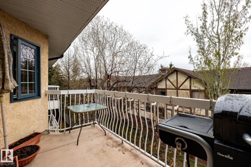 Balcony with concrete flooring and white metal railings, featuring an exterior wall with a textured finish and a casement window with muntins - #310 17151 94A Av Nw, Edmonton, AB - Outdoor With Exterior