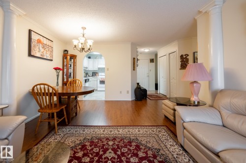 Open-concept living space featuring wood-finish flooring, an arched doorway, and crown molding - #310 17151 94A Av Nw, Edmonton, AB - Indoor Photo Showing Living Room