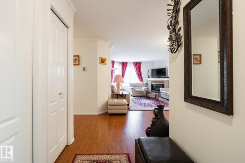 Entrance hallway featuring wood-finish flooring and a white bi-fold closet door - #310 17151 94A Av Nw, Edmonton, AB - Indoor Photo Showing Other Room