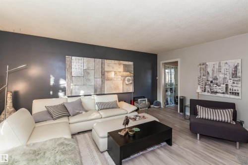 Living area featuring light wood-finish flooring and a partial dark accent wall - 13208 128 Avenue Nw, Edmonton, AB - Indoor Photo Showing Living Room