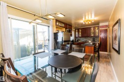 Dining area featuring a glass-top table, wood-finish flooring, and direct access to an outdoor patio through sliding glass doors - 