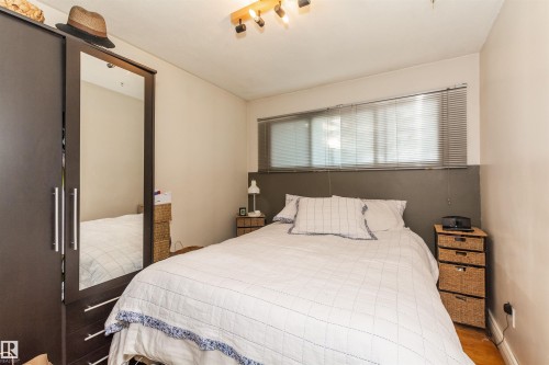 Bedroom featuring wood-finish flooring and a built-in wardrobe with mirrored doors - 13208 128 Avenue Nw, Edmonton, AB - Indoor Photo Showing Bedroom