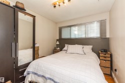 Bedroom featuring wood-finish flooring and a built-in wardrobe with mirrored doors - 