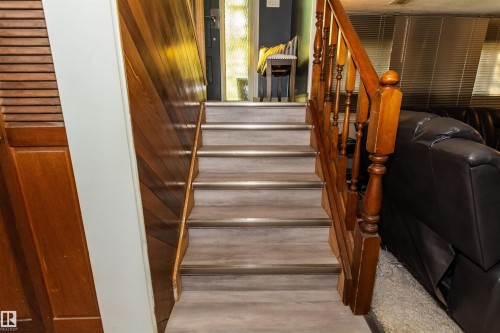 Staircase featuring wood-finish treads with metallic risers, a classic wood balustrade, and wood wall paneling - 13208 128 Avenue Nw, Edmonton, AB - Indoor Photo Showing Other Room