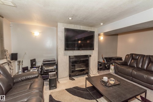 Living area featuring a textured ceiling, recessed lighting, and sconce fixtures - 13208 128 Avenue Nw, Edmonton, AB - Indoor Photo Showing Living Room With Fireplace