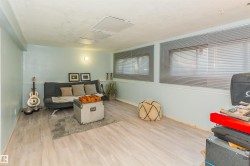 Spacious room featuring light wood-finish flooring, light blue walls with white trim, and multiple windows with horizontal blinds - 