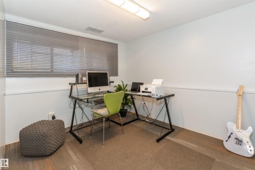 Room featuring white walls with a chair rail, a large window with horizontal blinds, and wood-finish flooring partially covered by a rug - 13208 128 Avenue Nw, Edmonton, AB - Indoor Photo Showing Office
