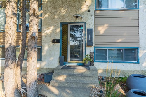Entryway featuring concrete steps, a security storm door, and contrasting siding with stucco and horizontal panels - 13208 128 Avenue Nw, Edmonton, AB - Outdoor