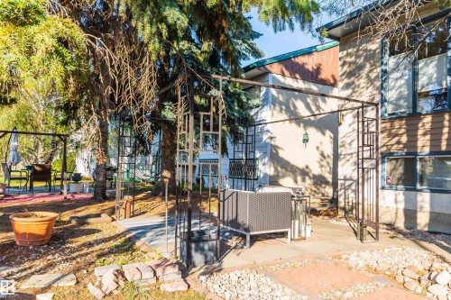 Expansive outdoor patio area featuring a metal gazebo structure, mature evergreen trees, and a combination of paved and gravel ground cover - 13208 128 Avenue Nw, Edmonton, AB - Outdoor