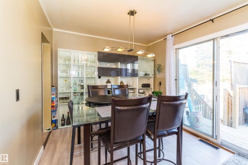Dining area featuring light wood-finish flooring and a contemporary linear pendant light fixture - 13208 128 Avenue Nw, Edmonton, AB - Indoor Photo Showing Dining Room