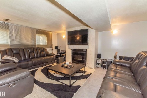 Living area featuring a floor-to-ceiling fireplace with integrated media center, wall-mounted light fixtures, and recessed lighting - 13208 128 Avenue Nw, Edmonton, AB - Indoor Photo Showing Living Room With Fireplace