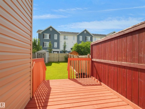 Expansive wood-finish deck with railings, offering access to a manicured lawn - 4487 Annett Common Sw, Edmonton, AB - Outdoor With Exterior