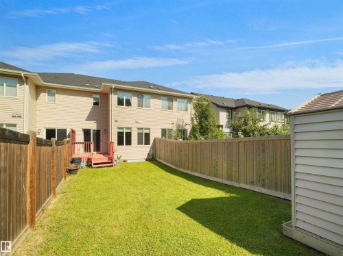 Fenced backyard featuring a wood deck, manicured lawn, and a storage shed - 4487 Annett Common Sw, Edmonton, AB - Outdoor With Exterior