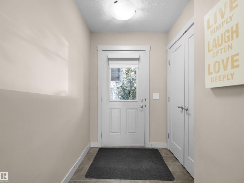 Entryway featuring a white door with a window, white trim, neutral-toned walls, and tile flooring - 4487 Annett Common Sw, Edmonton, AB - Indoor Photo Showing Other Room