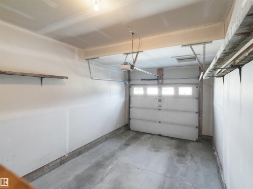 Single-bay garage featuring a concrete floor and white paneled garage door with upper window inserts - 4487 Annett Common Sw, Edmonton, AB - Indoor Photo Showing Garage