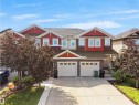 Multi-level exterior featuring red and beige siding, stone accents, multiple gables, and two integrated garages with concrete driveways - 4487 Annett Common Sw, Edmonton, AB  - Outdoor With Facade 