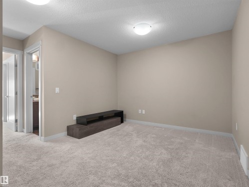 Plush gray carpeting extends throughout this room, featuring neutral beige walls and white trim - 4487 Annett Common Sw, Edmonton, AB - Indoor Photo Showing Other Room