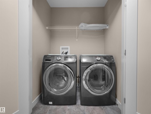 Dedicated laundry alcove featuring neutral-toned walls, tile flooring, and a white wire shelf - 4487 Annett Common Sw, Edmonton, AB - Indoor Photo Showing Laundry Room