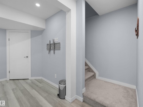 Basement area featuring wood-finish flooring, light blue painted walls, and white trim - 4487 Annett Common Sw, Edmonton, AB - Indoor Photo Showing Other Room