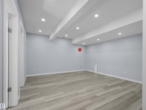 Spacious room featuring light wood-finish flooring, recessed lighting, light blue walls, white trim, and a white ceiling with exposed beams - 4487 Annett Common Sw, Edmonton, AB - Indoor Photo Showing Other Room