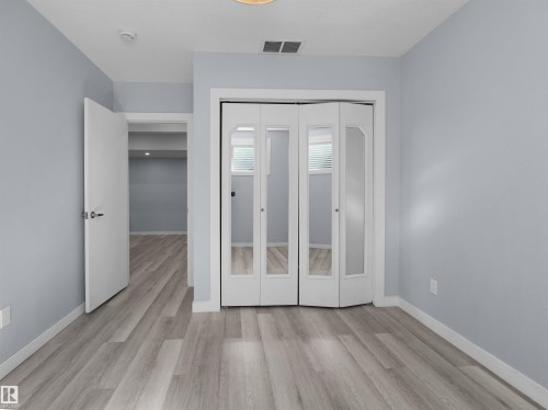 Light gray wood-finish flooring complements soft blue-gray walls - 4487 Annett Common Sw, Edmonton, AB - Indoor Photo Showing Other Room