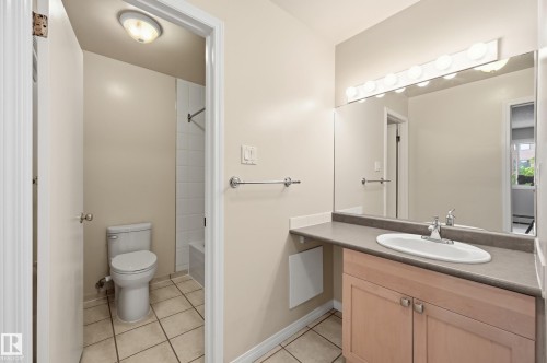 Bathroom featuring a vanity with an integrated sink, a large wall-mounted mirror, and a wall-mounted light fixture - #433 11217 103 Av Nw, Edmonton, AB - Indoor Photo Showing Bathroom
