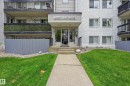 Multi-story building entrance featuring a concrete walkway, manicured lawn areas, decorative rock landscaping, and a privacy fence - #433 11217 103 Av Nw, Edmonton, AB  - Outdoor With Balcony 