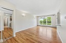 Spacious living area featuring expansive wood-finish flooring, a large window with a black wrought iron balcony, and two wall sconces - #433 11217 103 Av Nw, Edmonton, AB  - Indoor Photo Showing Other Room 