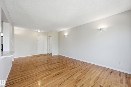 Spacious room with wood-finish flooring, white baseboards, and neutral wall paint - #433 11217 103 Av Nw, Edmonton, AB - Indoor Photo Showing Other Room