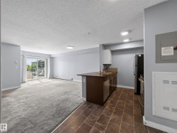 Open-concept living space featuring a sliding glass door to a private balcony, light gray carpeting, and recessed lighting - 