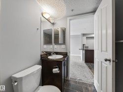 Bathroom featuring a dark wood-finish vanity, white ceramic sink, and a wall-mounted light fixture - 