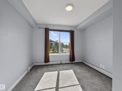 Carpeted room featuring a large window, neutral wall paint, and baseboard heating - 