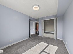 Carpeted room featuring light blue walls, a ceiling-mounted light fixture, white trim, and a bi-fold closet with shelving - 