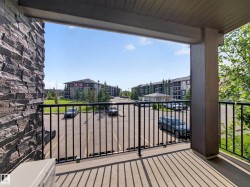 Private balcony featuring a black metal railing, concrete flooring, and a stacked stone wall accent - 