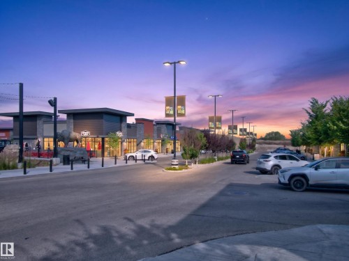 Retail frontage featuring modern architectural design with stone accents, storefront windows, and exterior lighting - #217 12045 22 Av Sw, Edmonton, AB - Outdoor
