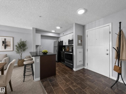 Kitchen and entry area featuring wood-finish tile flooring - #217 12045 22 Av Sw, Edmonton, AB - Indoor