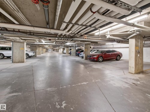 Spacious underground parking garage with concrete flooring and structural columns - #217 12045 22 Av Sw, Edmonton, AB - Indoor Photo Showing Garage
