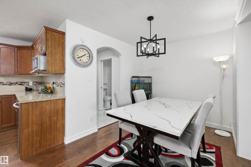 Dining area featuring wood-finish flooring, a contemporary chandelier, and an arched doorway - 2803 12 Street Nw, Edmonton, AB - Indoor Photo Showing Other Room