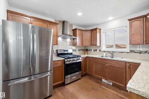 Kitchen featuring stainless steel appliances, wood-finish flooring, recessed lighting, wood cabinetry, and a double basin sink - 2803 12 Street Nw, Edmonton, AB - Indoor Photo Showing Kitchen With Stainless Steel Kitchen With Double Sink