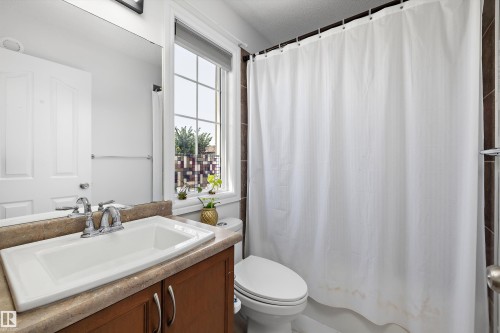 Bathroom featuring a window with grid detailing, wood-finish vanity with countertop, and an integrated white sink - 2803 12 Street Nw, Edmonton, AB - Indoor Photo Showing Bathroom