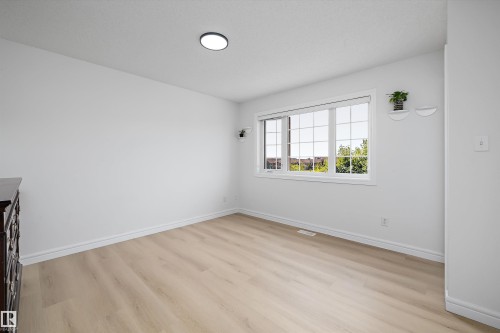 Light-filled interior featuring expansive window, wood-finish flooring, white baseboards, and a flush-mount ceiling light - 2803 12 Street Nw, Edmonton, AB - Indoor Photo Showing Other Room